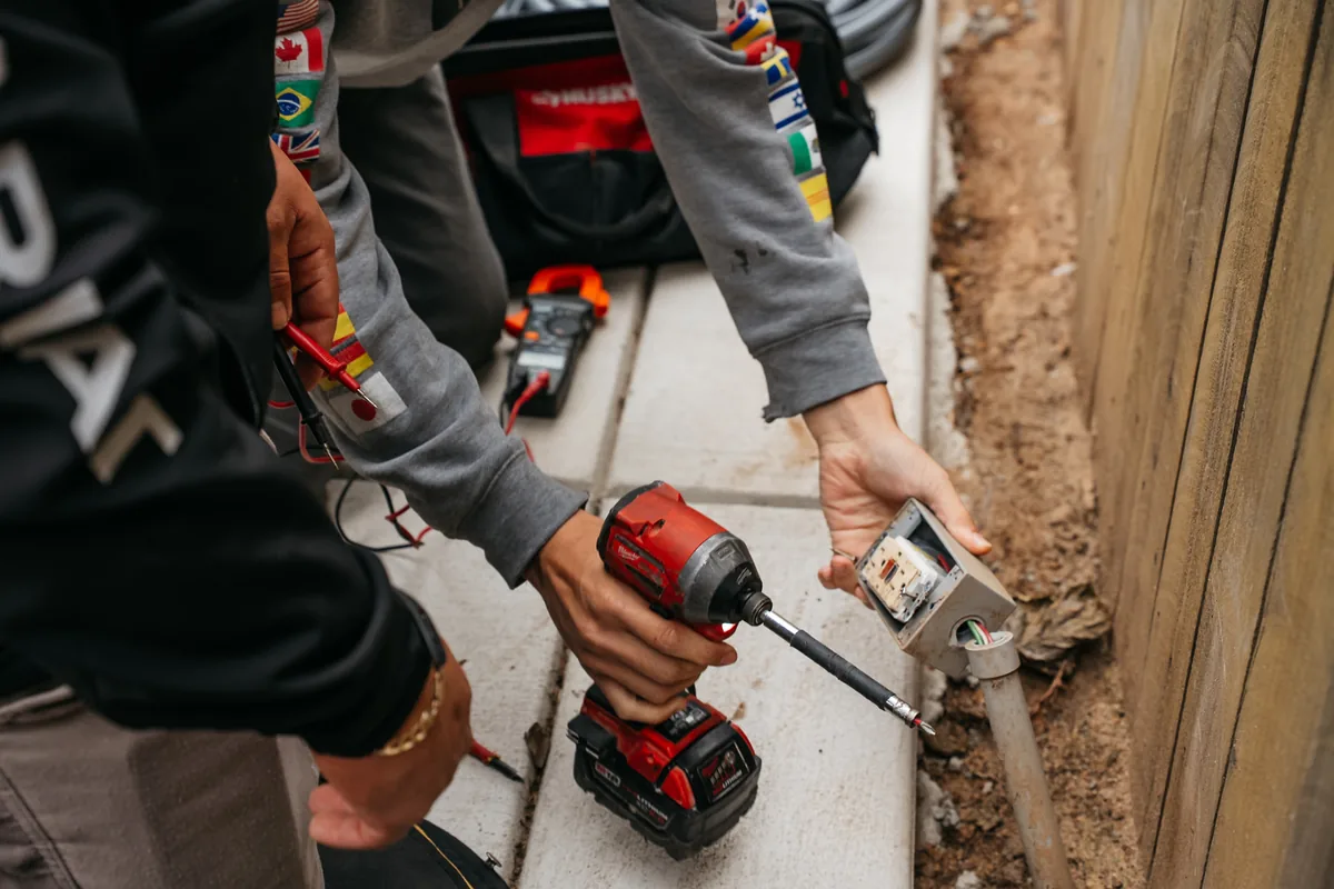 Licensed electrician wiring an outlet during a whole house fan installation in a Fresno home